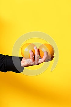 Hand holding a orange frut on yellow background photo