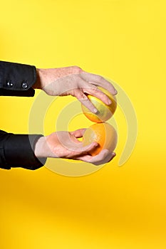hand holding a orange frut on yellow background photo