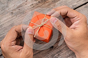 Hand Holding Orange Gift Box and Yellow Ribbon