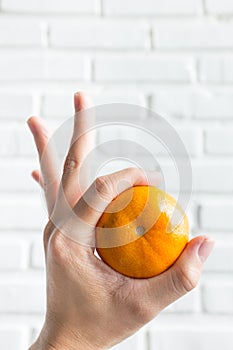 hand holding orange in Okay gesture