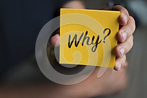 Hand holding an orange Paper with the word why - Why?, Business Concept