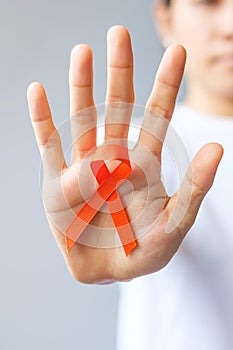 Hand holding Orange Ribbon for Leukemia, Kidney cancer day, world Multiple Sclerosis, CRPS, Self Injury Awareness month.