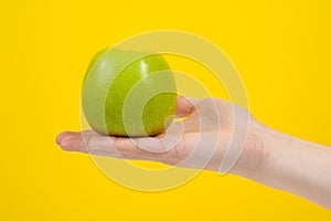 Hand holding organic green delicious apple Isolated on yellow Background. Healthy eating and dieting concept
