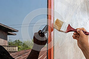 Hand holding paint brush on wood wall new house at construction site
