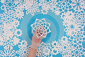 Hand holding paper snowflake on blue background. Top view. Christmas decoration