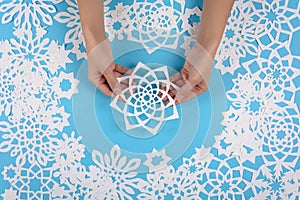 Hand holding paper snowflake on blue background. Top view. Christmas decoration