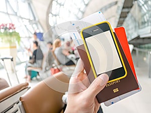 Hand holding passport, boarding pass and smart phone in airport