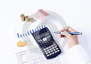 Hand holding pen and calculator and house paper and coins stack