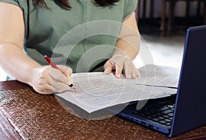 Hand holding pen marking on paperwork in office