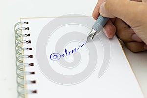 Hand holding pen and write text `online`. Image use for network, internet, business concept