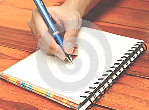 Hand holding a pen writing on the notebook