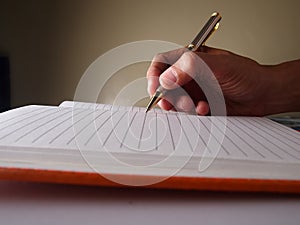 Hand holding a pen and writing on a notebook