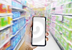 Hand holding phone for shopping online supermarket with blurred supermarket background.E-commerce and technology concept