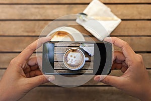 hand holding phone taking coffee photo on table