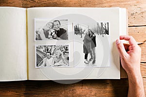 Hand holding photo album with pictures of senior couple. Studio