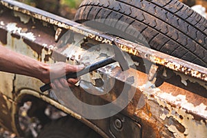 Hand holding a pickup truck hammer rusty peeling paint tires old car wheels vintage