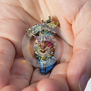 A hand holding a piece of Bizmuth