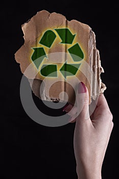 Hand holding a piece of  Cardboard With Recycle Symbol