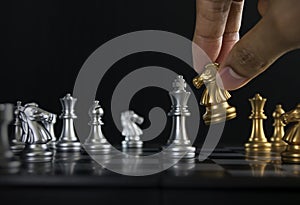 Hand holding a piece of chess knight or horse to win the game on black background. Checkmate, success, business strategy,