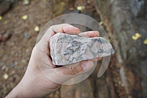 Hand holding a piece of feldspar rock on nature background.