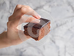 Hand holding a piece of freshly baked brownie