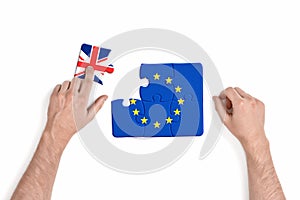 Hand holding piece of jigsaw puzzle with European Union and Great Britain flag isolated on white background