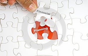 Hand holding piece of jigsaw puzzle with word FINANCIAL PLANNING