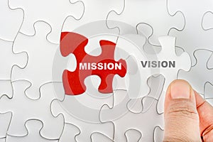 Hand holding piece of jigsaw puzzle with word MISSION VISION