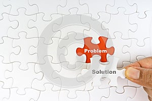 Hand holding piece of jigsaw puzzle with word PROBLEM SOLUTION