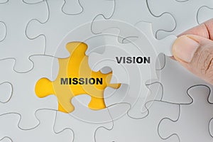 Hand holding piece of jigsaw puzzle with word VISION MISSION