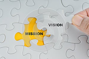 Hand holding piece of jigsaw puzzle with word VISION MISSION photo