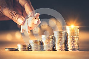 Hand holding a piggy bank on coins stack. Creative ideas for saving money concept.