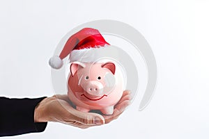 Hand holding piggy bank wearing Santa hat on white background. Christmas shopping concept