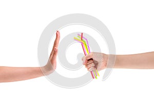 Hand holding pile of colorful plastic drinking straws with hand making gesture rejection.