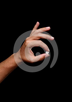 Hand holding a pill on a black background. Prescripted medicaments in white tablets. Medical care and treatment concept.