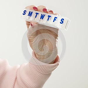 Hand holding pill box.