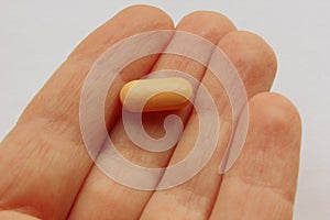 Hand holding the pill in the palm of the hand.  on a white background.