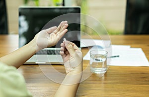 Hand holding pills with glass of water for aching