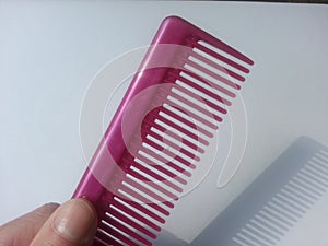 Hand holding pink comb