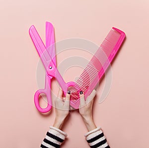 Hand holding pink scissors and comb