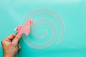 Pink origami unicorn on cyan blue background