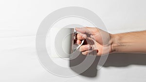 A hand holding a plain white ceramic mug against a white background