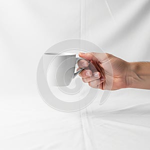 A hand holding a plain white ceramic mug against a white background
