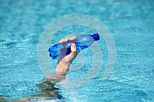 Hand holding plastic bottle of water on the surface of water