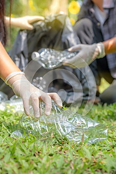 Hand holding plastic bottles waste, Couple picking up trash putting to the black garbage bag at Sunflower Park on Environmental