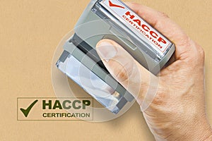 Hand holding a plastic stamp with HACCP certification Hazard Analyses and Critical Control Points text - Food Safety and Quality