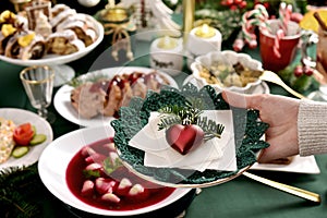 A hand holding a plate with  Christmas Eve wafer over the festive table