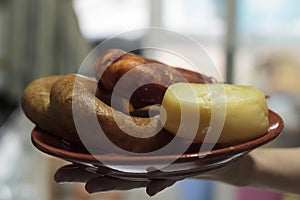 Hand holding a plate with artesan cheese and portuguese sausage photo