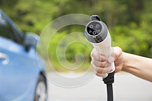 Hand holding plug in connector for Charging electric car