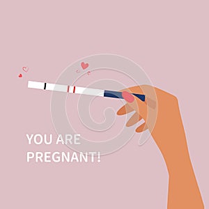 Hand holding positive pregnancy test